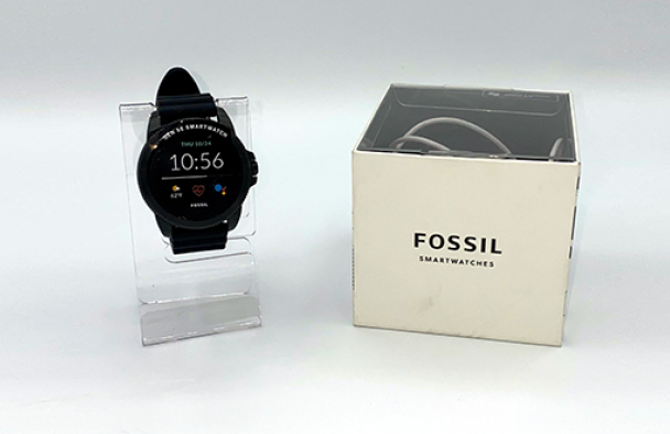 A fossil smart watch is on display with a grey background. The box it came in is sitting to the right of the watch.